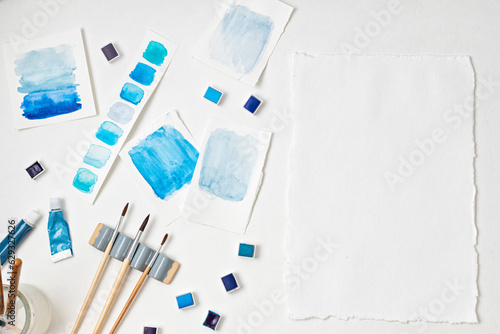 Artist painting watercolor palettes in blue pastel with brushes. Craft artistic background. Recomforting, destressing hobby, art therapy