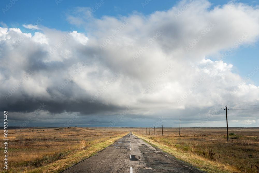 View of an old abandoned road in the steppe beautiful landscape with clouds. Freedom and travel.