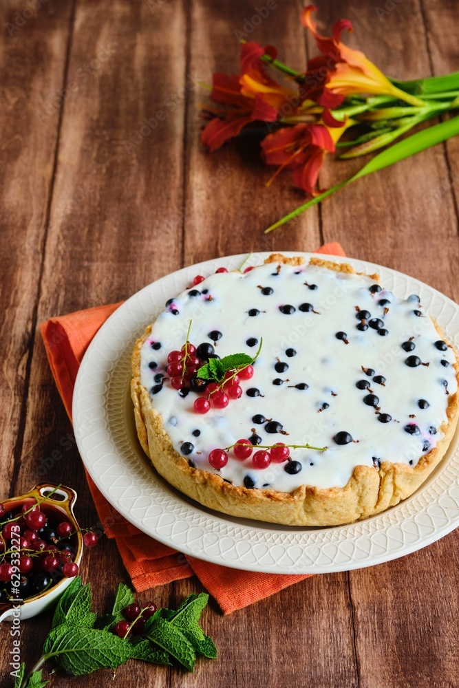 Dessert, a whole round cheesecake with blackcurrant on shortcrust pastry on a ceramic plate on a wooden background. Summer desserts, pastries with berries. Dessert, a whole round cheesecake with blackcurrant on shortcrust pastry on a ceramic plate on a wooden background. Summer desserts, pastries with berries.