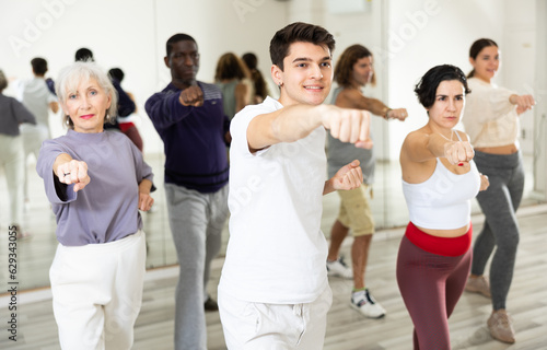 Group of active people practice sport dancing by taking part in a dance studio