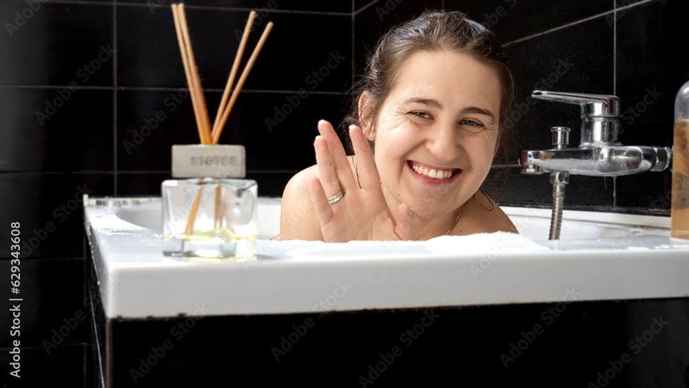 Woman taking a relaxing bath, smiling towards the camera. Concept of maintaining good hygiene and self-care Woman taking a relaxing bath, smiling towards the camera. Concept of maintaining good hygiene and self-care