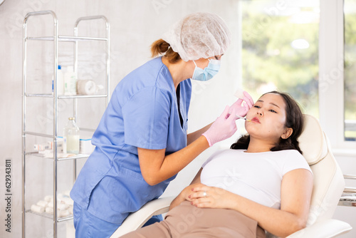 Skilled cosmetologist performing procedure for injecting beauty injections for the patient