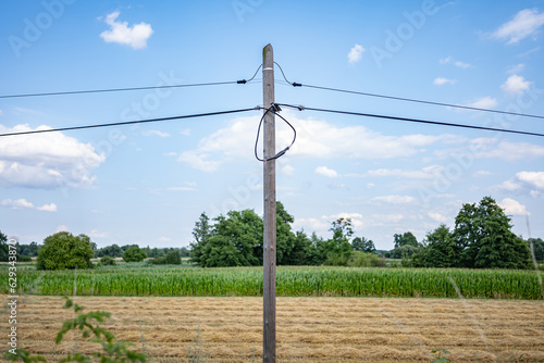 krajobraz linii elektrycznej pośrodku zielonych pól w zachodniej Polsce, jasne zielono niebieskie kolory lekko pochmurna pogoda photo