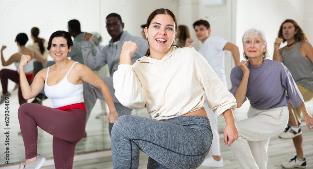 Obraz premium Portrait of cheerful young girl enjoying active dancing during group training in dance studio..