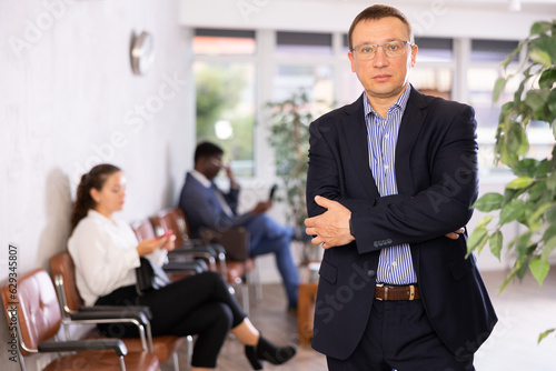 Adult man in business suit and glasses posing in office reception