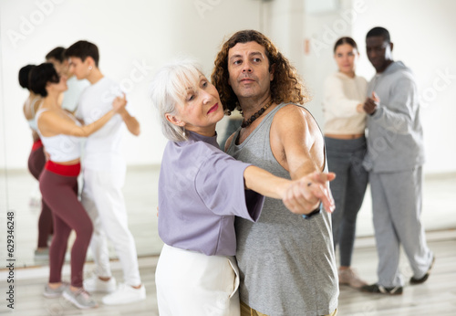 Dancing positive couple learns a slow foxtrot in a lesson in a dance studio