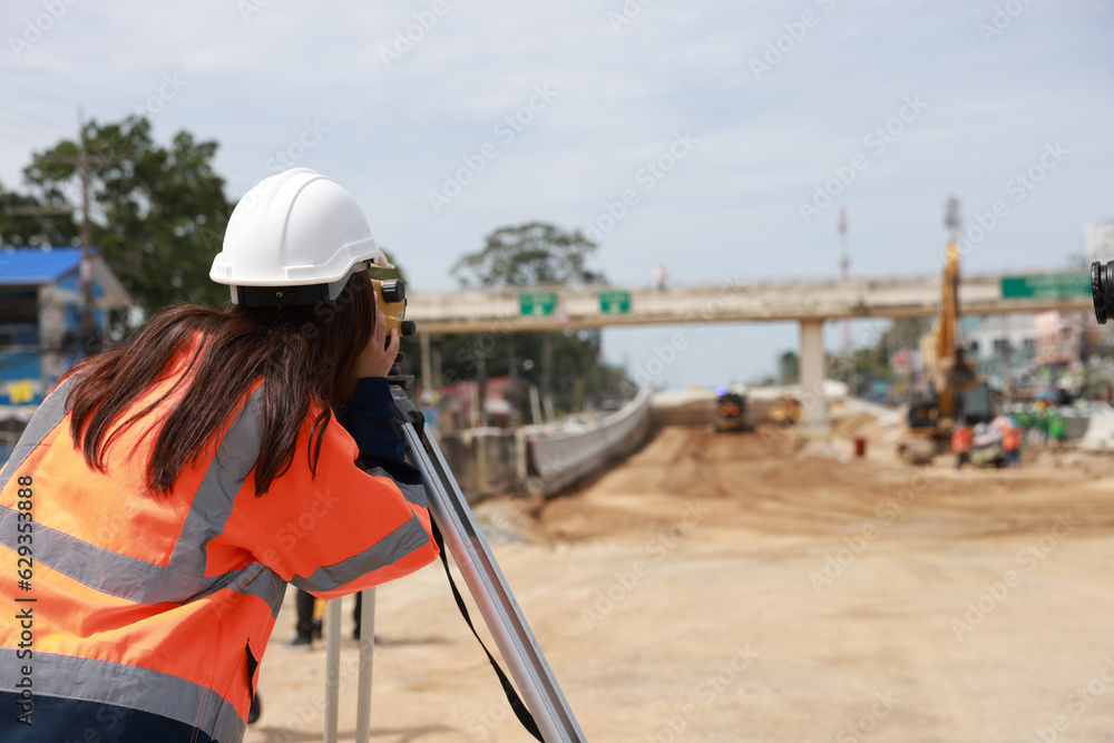 Site female  engineer operating her instrument during roadworks. Builder using total positioning station tachymeter on construction