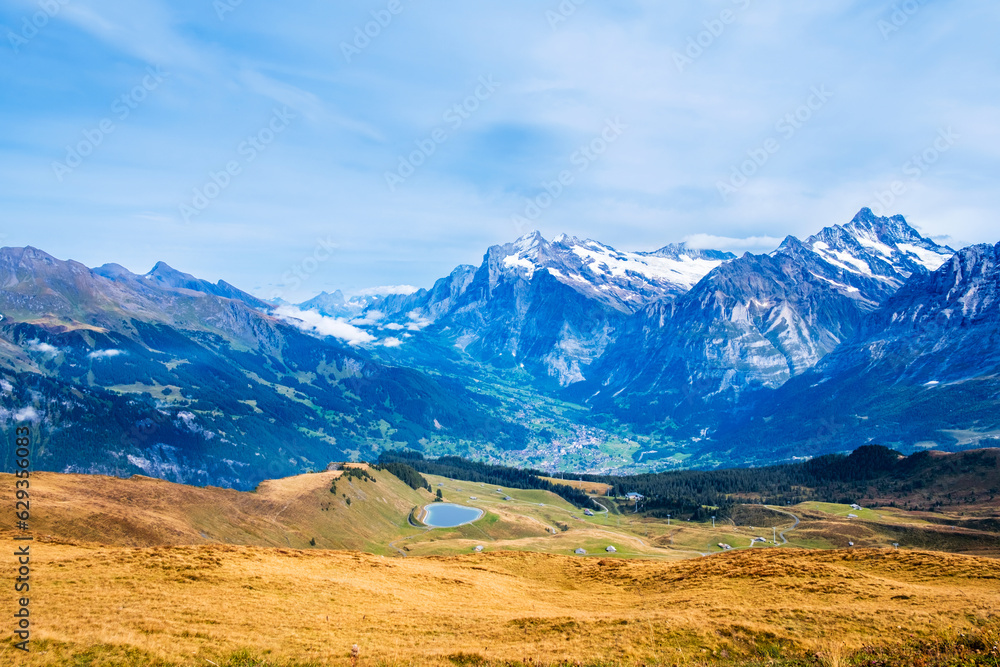 Autumn view over Grindelwald valley and Swiss Alps. Mountain range of peaks Wetterhorn and Schreckhorn from Mannlichen near Wengen and Lauterbrunnen, Switzerland