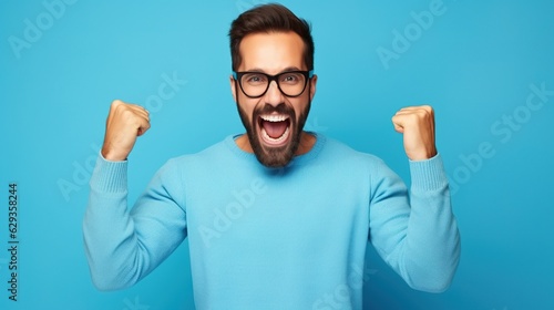 young handsome man with beard wearing casual sweater and glasses over blue background very happy and excited doing winner gesture with arms raised, smiling, generative ai photo