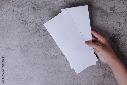 Hand holding white blank flyer over gray background to replace your design photo