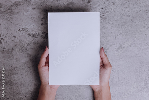 Hand holding A5 template blank paper mockup on gray background