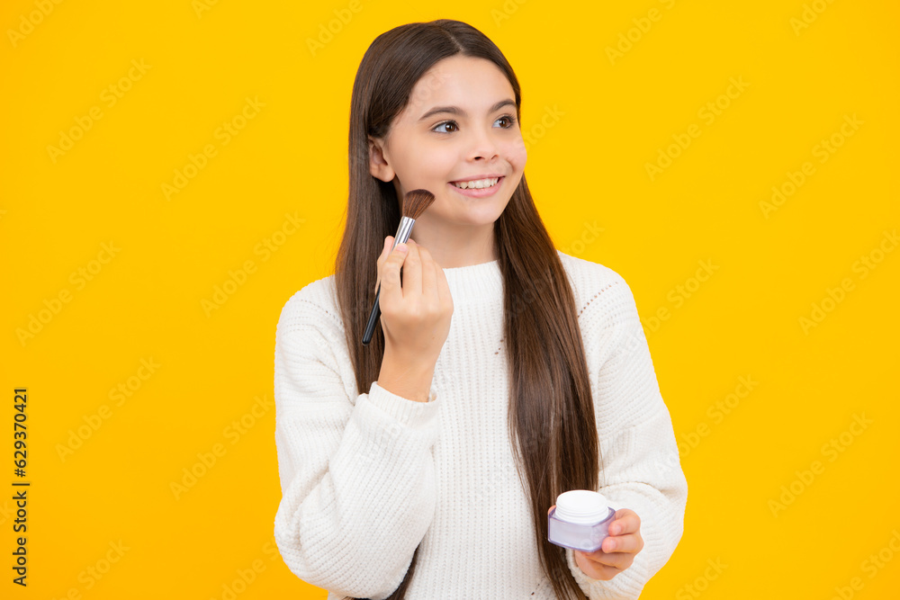 Teenage girl making beauty make up, hold powder and brush. Beautiful teen applying makeup using powder brush isolated on yellow background. Teenage girl making beauty make up, hold powder and brush. Beautiful teen applying makeup using powder brush isolated on yellow background.
