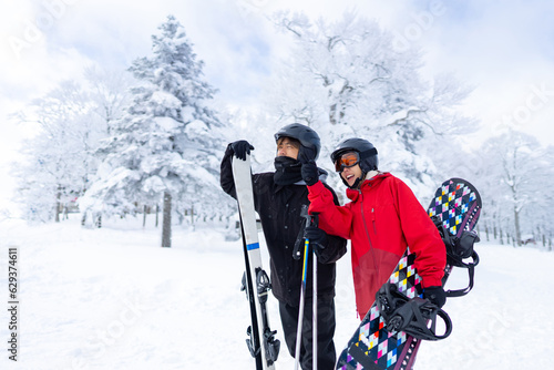 Asian man and woman practice freeriding snowboard and ski on snowy mountain at ski resort. People enjoy outdoor active lifestyle travel nature and winter extreme sport training on holiday vacation.