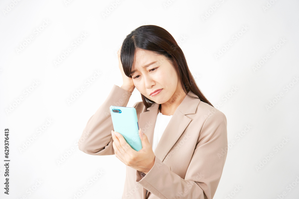 スマートフォンを見て悩むミドルエイジのビジネスウーマン　白背景