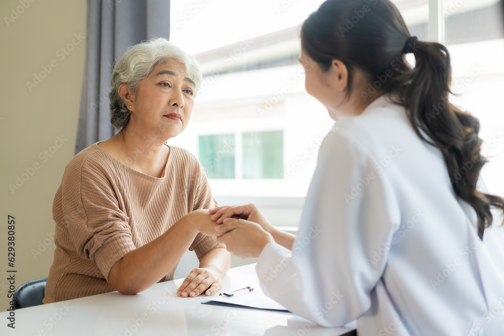 Fototapeta premium Family doctor examining smiling asian old woman using stethoscope at hospital An old woman talks and consults with a doctor about osteopathy. Health and wellness concept