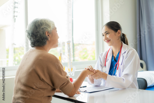 Family doctor examining smiling asian old woman using stethoscope at hospital An old woman talks and consults with a doctor about osteopathy. Health and wellness concept