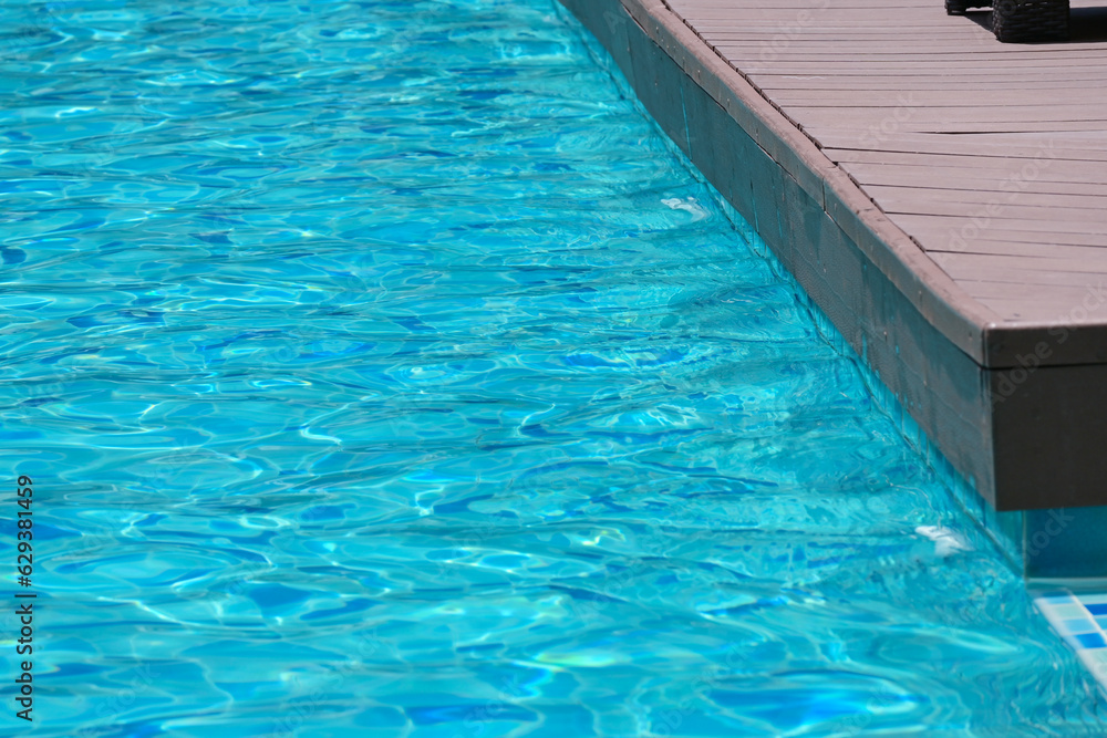 surface of blue swimming pool with brown wood balcony, freshness water background