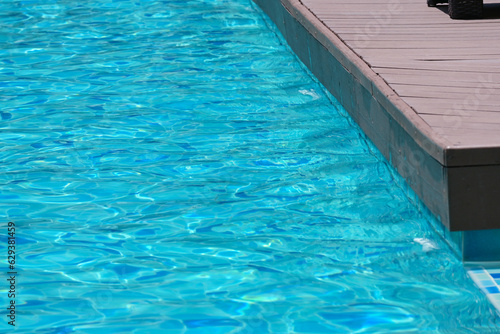 surface of blue swimming pool with brown wood balcony, freshness water background