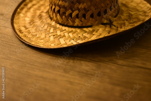 Sombrero de trabajo en el campo. Cosido de paja, y un cordon negro, sobre mesa de madera. Plano con medio sombrero en la parte superior del plano. Enfoque en las costuras. photo
