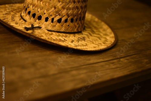 Sombrero de trabajo en el campo. Cosido de paja, y un cordon negro, sobre mesa de madera. Plano holandes. photo