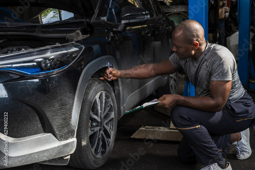 Black car mechanic man working in auto repair shop