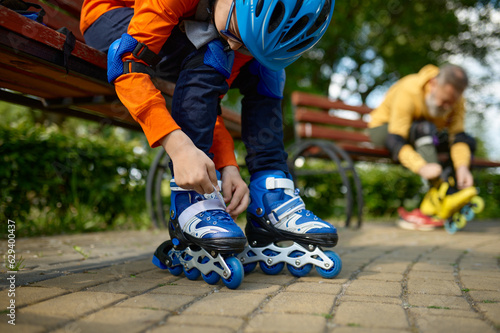 Selective focus of grandson and grandfather putting on roller skates