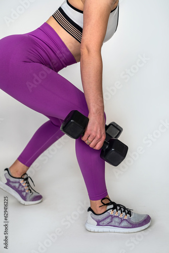 young sporty woman learning exercises with dumbbells isolated on a white studio background.