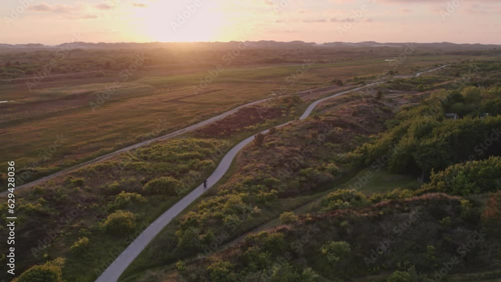 Man is cycling on gravel path at Terschelling island during sunset, aerial Man is cycling on gravel path at Terschelling island during sunset, aerial