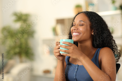 Happy black woman breathing drinking coffee at home