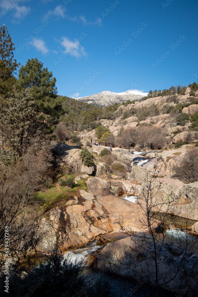 Fotografía de las majestuosas montañas de La Pedriza con el río serpenteante: La imagen muestra un paisaje impresionante de las imponentes montañas de La Pedriza que se elevan hacia el cielo. 