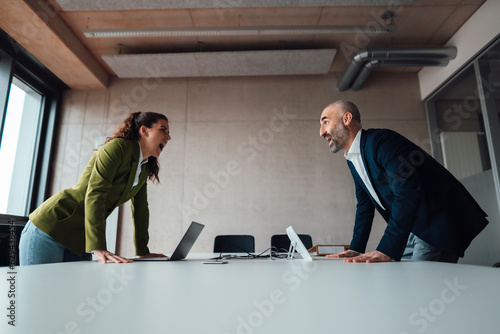 Businesswoman arguing with businessman at desk in office photo