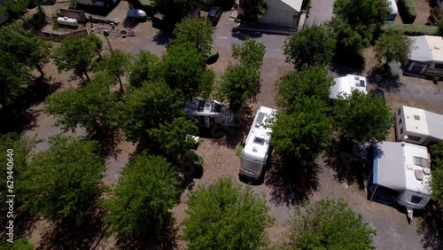 Aerial over camping place, parked camping vans among the trees during sunny day, traveling and taking vacation concept. Location south of France.