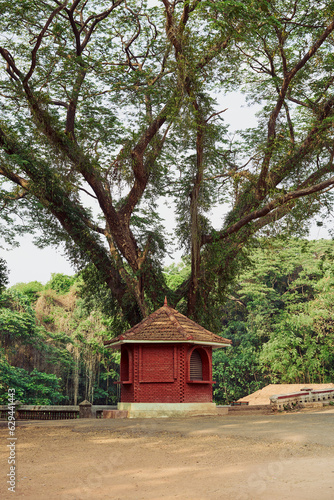 A red brick booth with tiled roof under a big tree