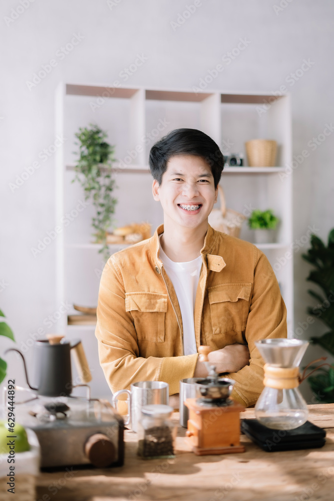 Asian male barista brewing coffee at the kitchen table. Asian male barista brewing coffee at the kitchen table.
