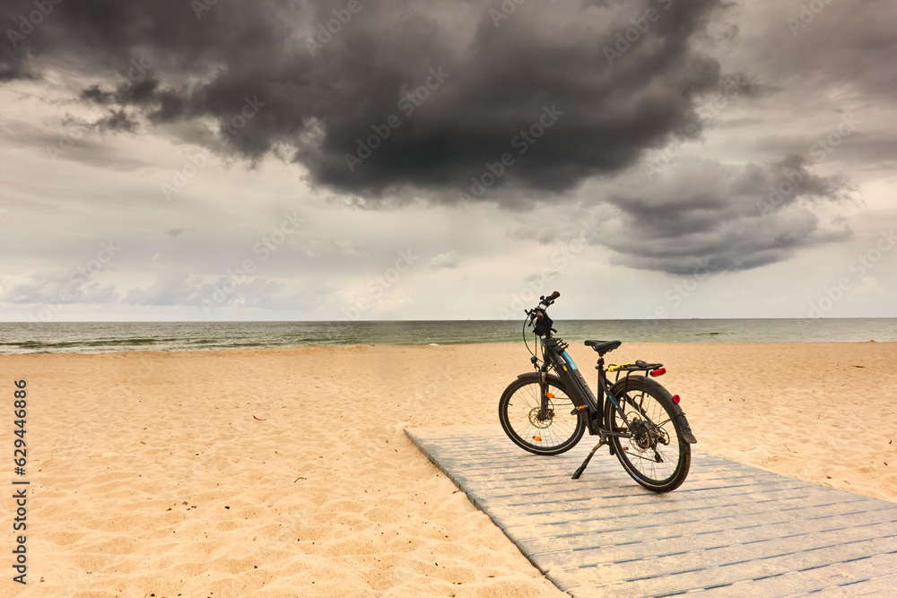 Bike parked on the beach of the Curonian Spit under dark clouds during a bike tour of Poland