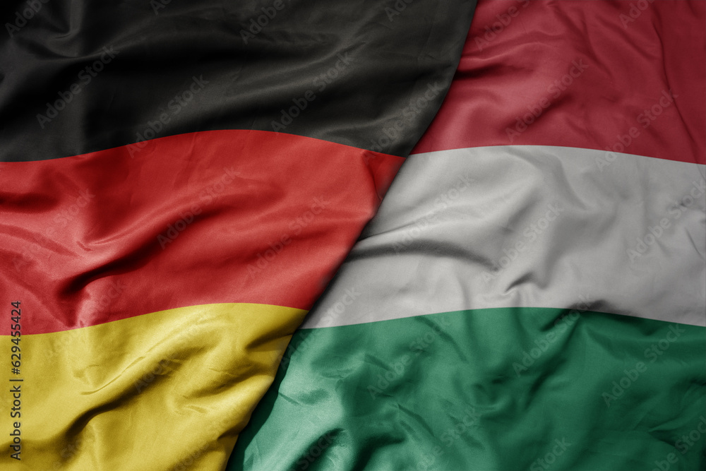 big waving realistic national colorful flag of germany and national flag of hungary .