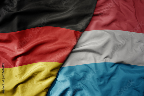 big waving realistic national colorful flag of germany and national flag of luxembourg .