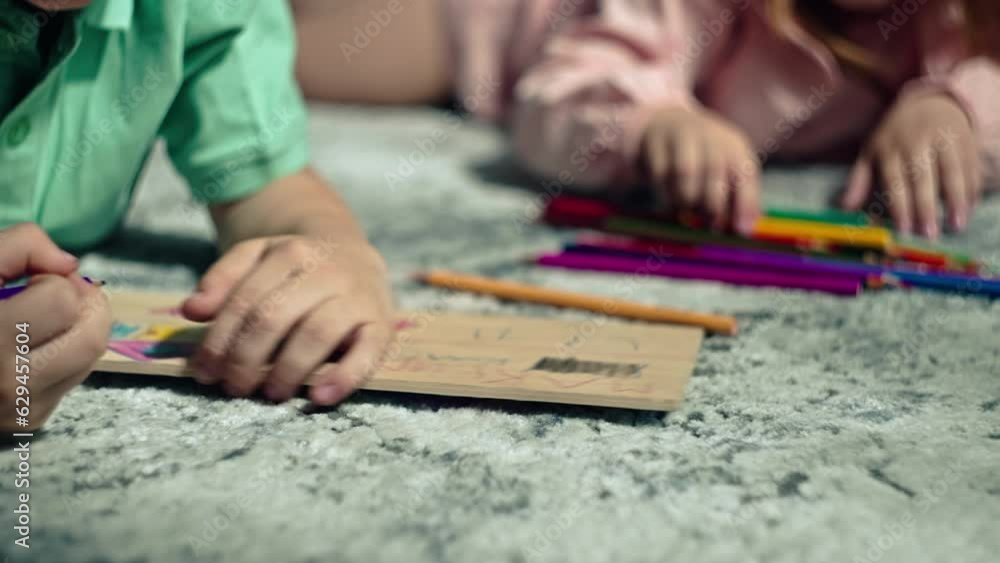 Brother and sister draw with pencils lying on the floor at home. Children have fun and are engaged in creativity. Happy carefree childhood. High quality 4k footage Brother and sister draw with pencils lying on the floor at home. Children have fun and are engaged in creativity. Happy carefree childhood. High quality 4k footage