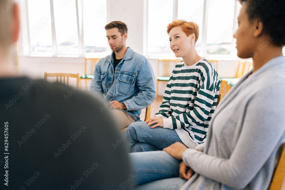Selective focus of young woman in group psychotherapy session telling about mental problem to other patients. Female talking about traumatic experience from past, despair and pain emotions. Selective focus of young woman in group psychotherapy session telling about mental problem to other patients. Female talking about traumatic experience from past, despair and pain emotions.