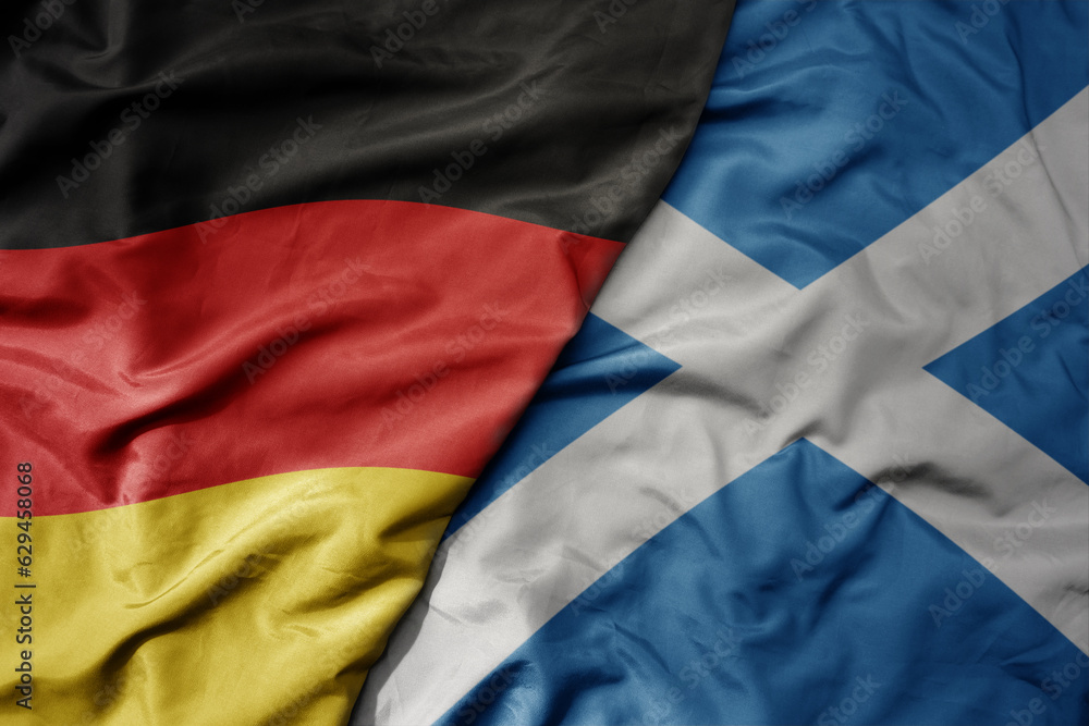 big waving realistic national colorful flag of germany and national flag of scotland .