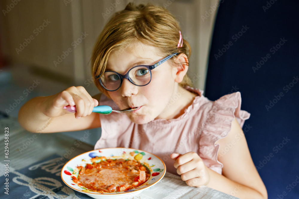 Little preschool girl eating from spoon vegetable potato soup. Healthy food for children. Happy kid at home or nursery. Little preschool girl eating from spoon vegetable potato soup. Healthy food for children. Happy kid at home or nursery.