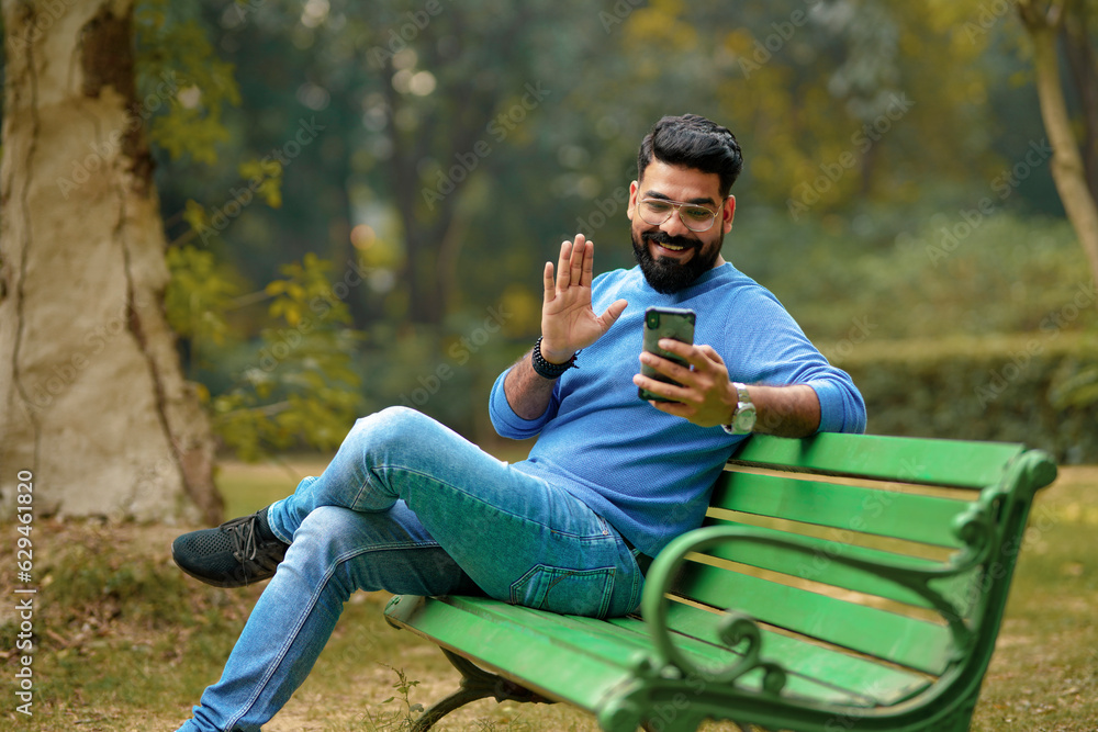 young indian man using smartphone at park. young indian man using smartphone at park.