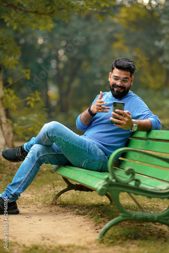 young indian man using smartphone at park. © Niks Ads