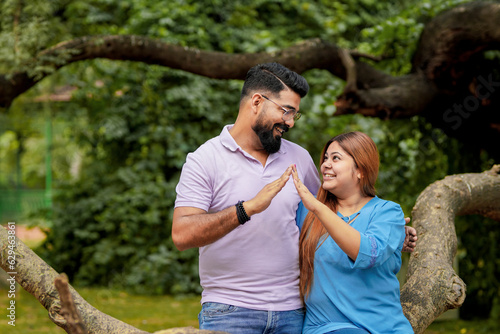Young indian couple making home shape with hand at park.
