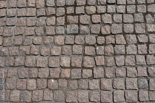 Uneven surface of pavement made of rectangular pink granite stone setts