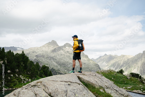 Young man standing on a rock with mountain background