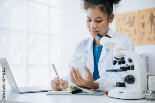 .Young scientists conducting research investigations in a medical laboratory, a researcher in the foreground is using a microscope in laboratory for medicine.