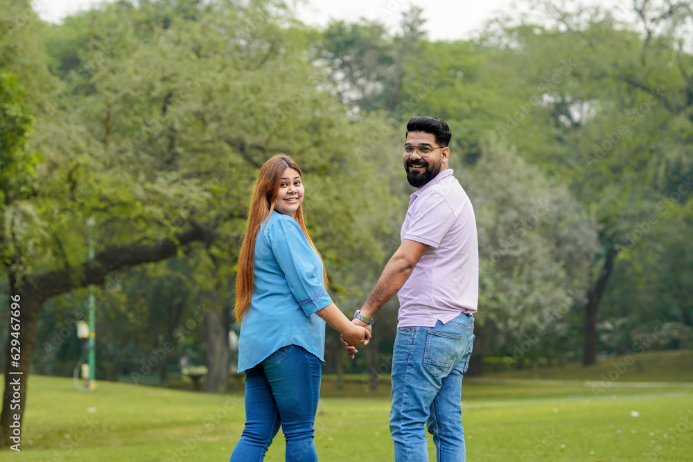 young indian couple holding hand each other and walking in park young indian couple holding hand each other and walking in park