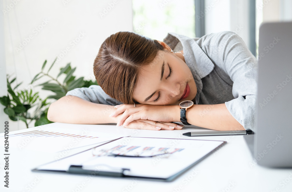 Overworked and tired businesswoman sleeping over a laptop in a desk at work in her office Overworked and tired businesswoman sleeping over a laptop in a desk at work in her office