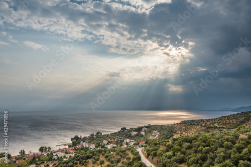 Scenic view of the Aegean sea against dramatic sky with sun rays during summer storm on Greece coastline